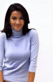 Hispanic woman smiling at camera in a blue turtleneck.