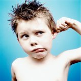 Portrait of a young boy pulling his ear and looking confused